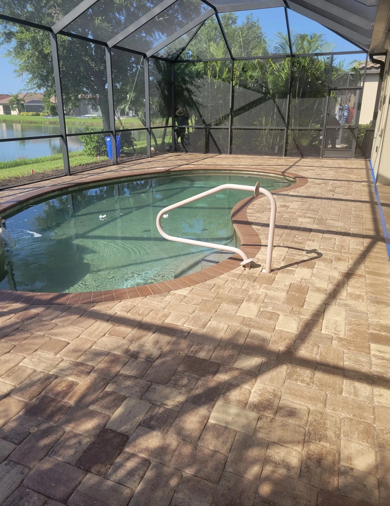 Sealed paver pool deck by the pool steps inside a screened pool cage in Venice, FL, after paver restoration