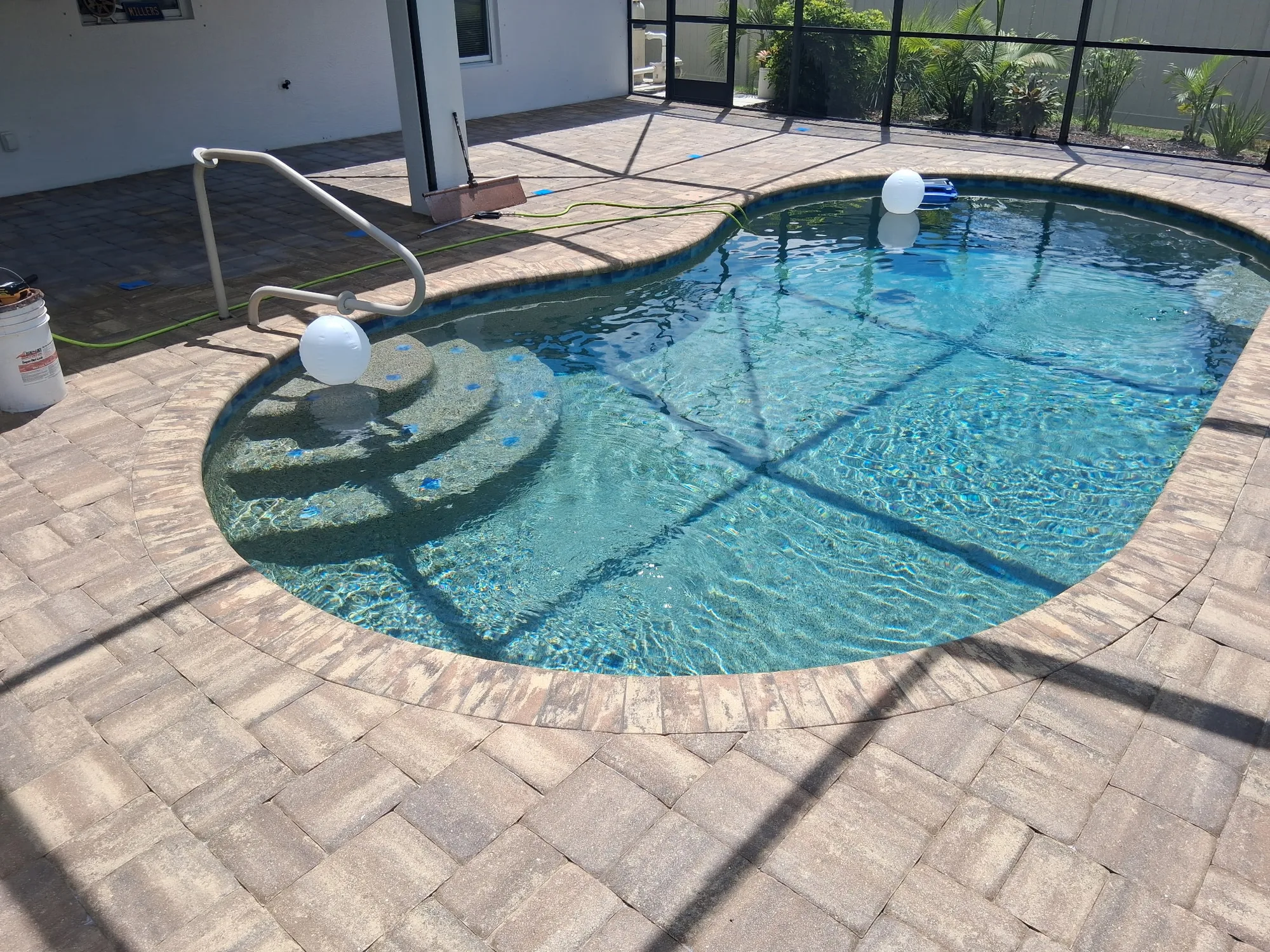 Paver pool deck by the pool steps in North Port, FL during seal prep, before stripping